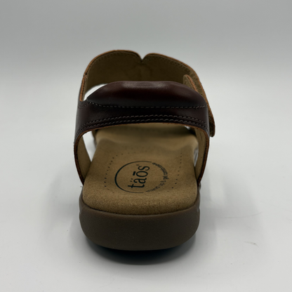 Brown sandal with 'taos' brand logo on a white background