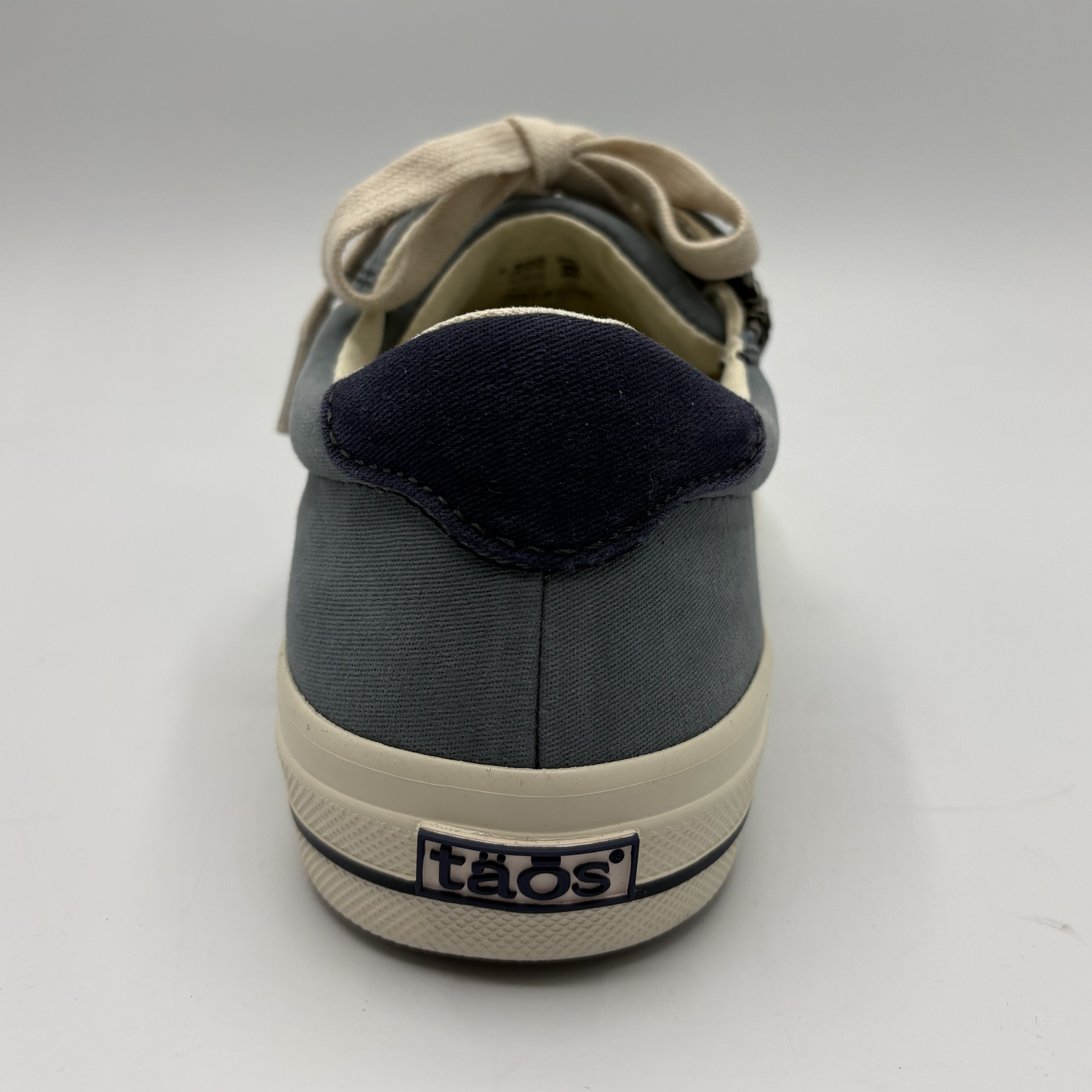 Gray sneaker with black sole and beige laces on a white background