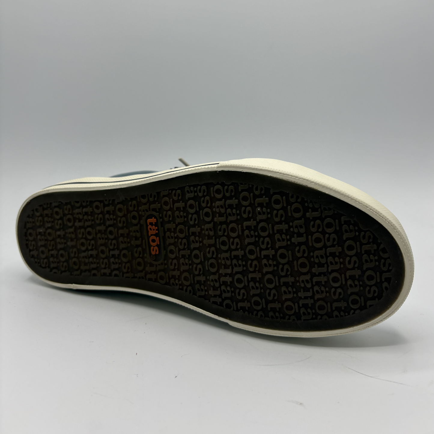 Close-up of a shoe sole with brand logo on a gray background