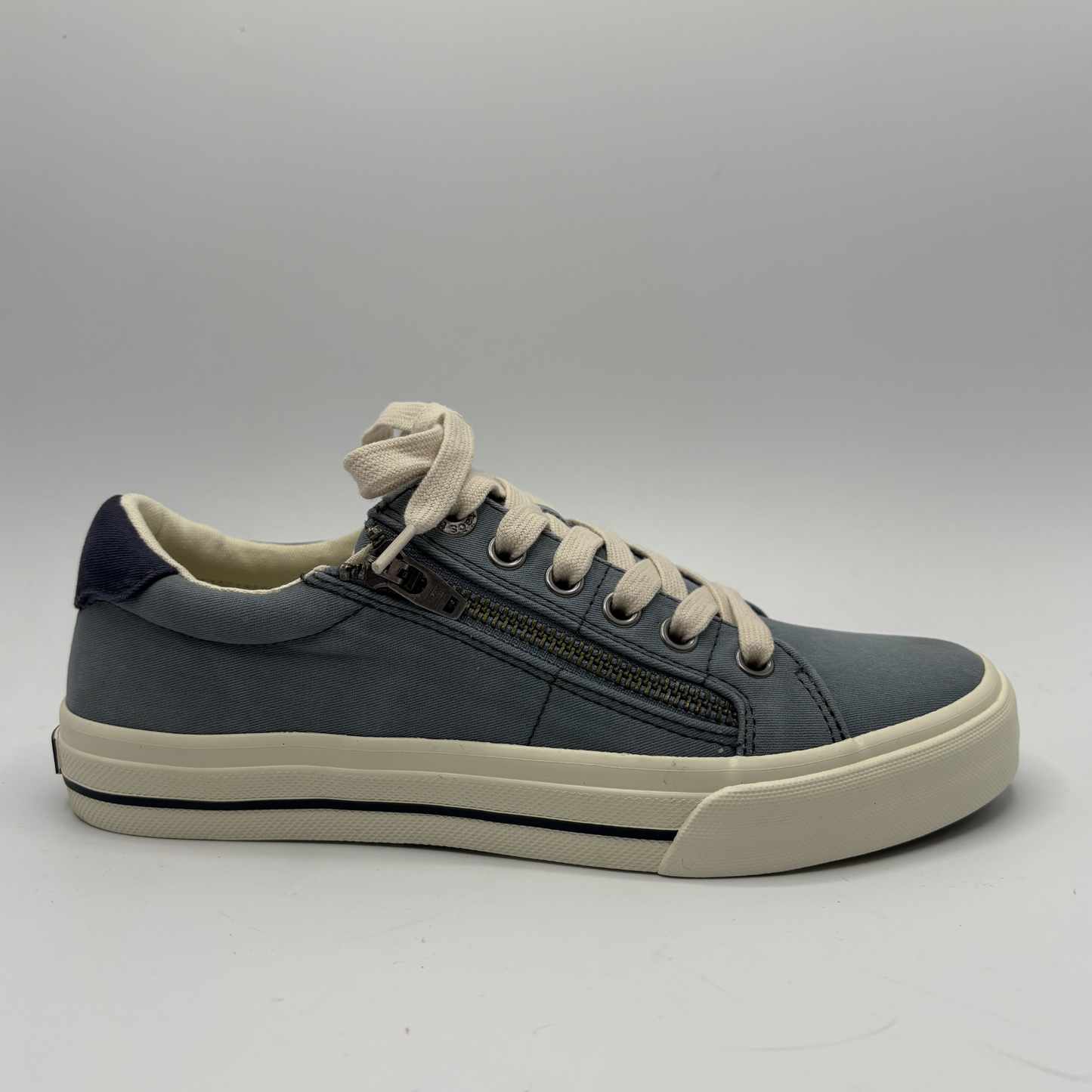 Blue sneaker with white laces on a gray background