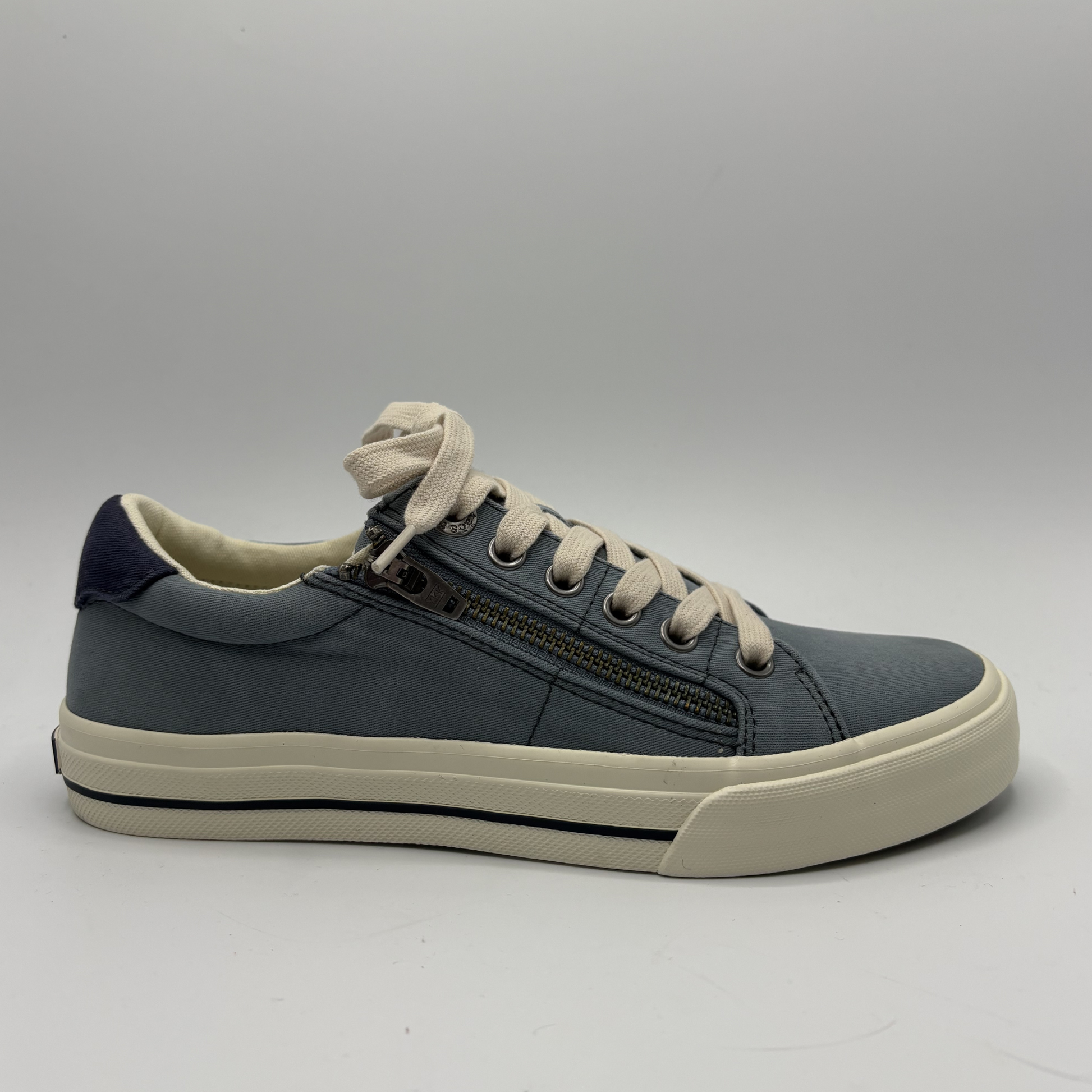 Blue sneaker with white laces on a gray background