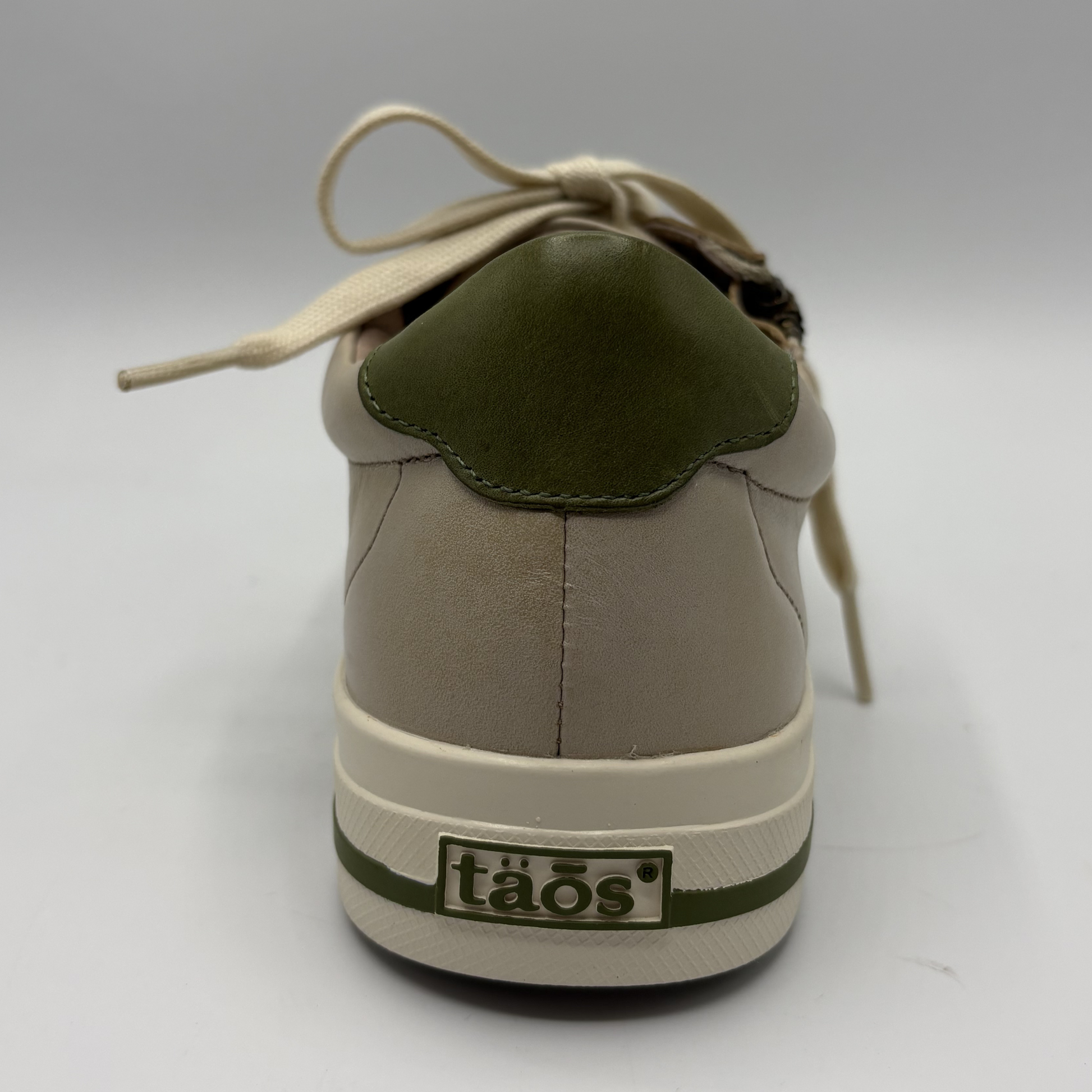 Beige sneaker with green accents on a white background