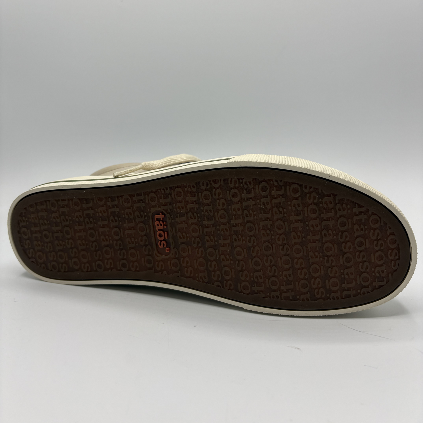 Close-up of a shoe sole with brand logo on a gray background