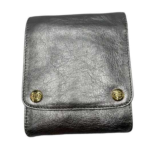 A front view of a square silver leather handbag with two gold snaps on the front.