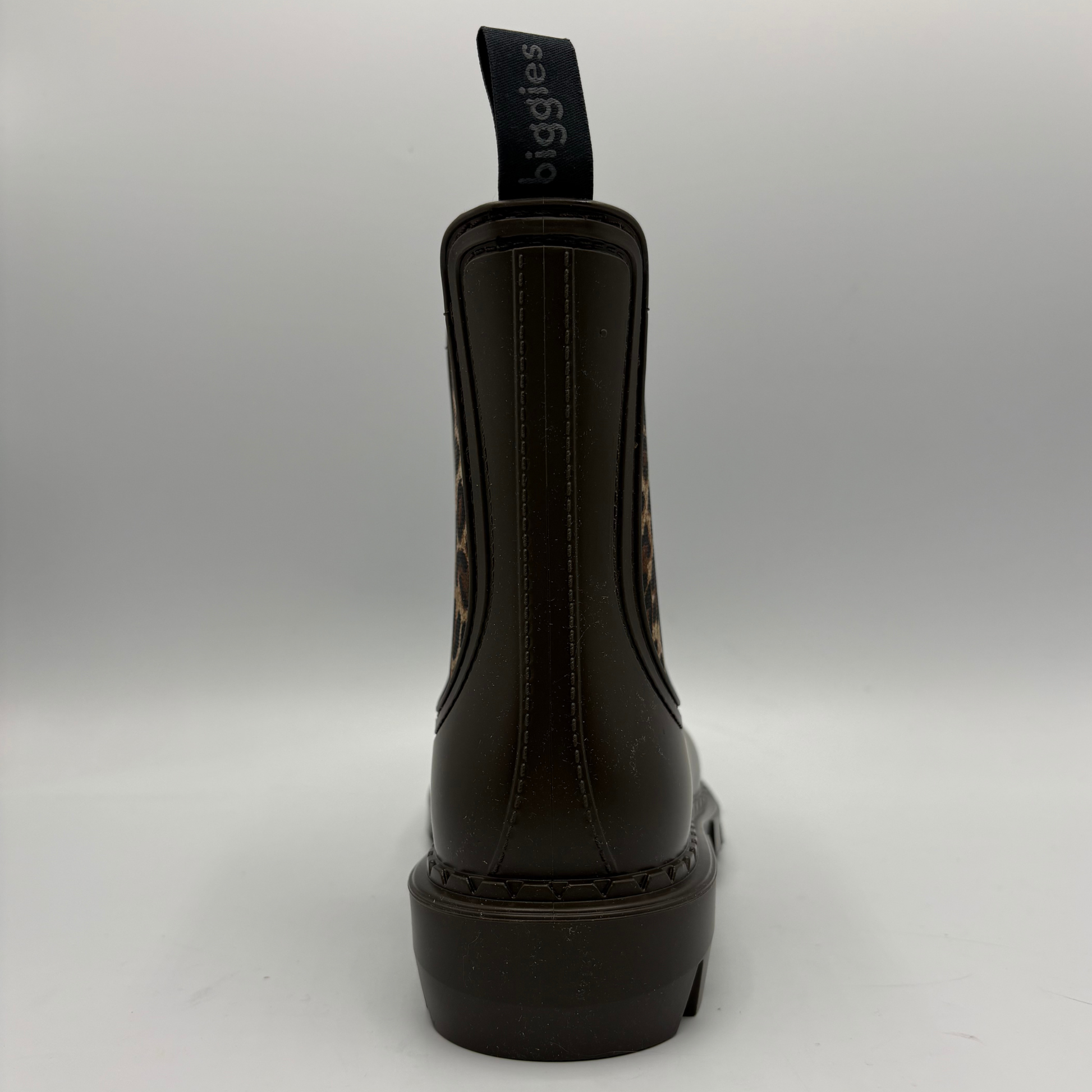 A single dark brown leather Chelsea boot shown from the back, featuring a black elastic gusset with a dark brown sole, and patterned detailing on the sides.