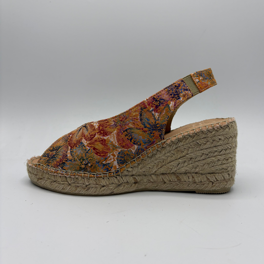 Wedge sandal with floral patterned strap on a white background