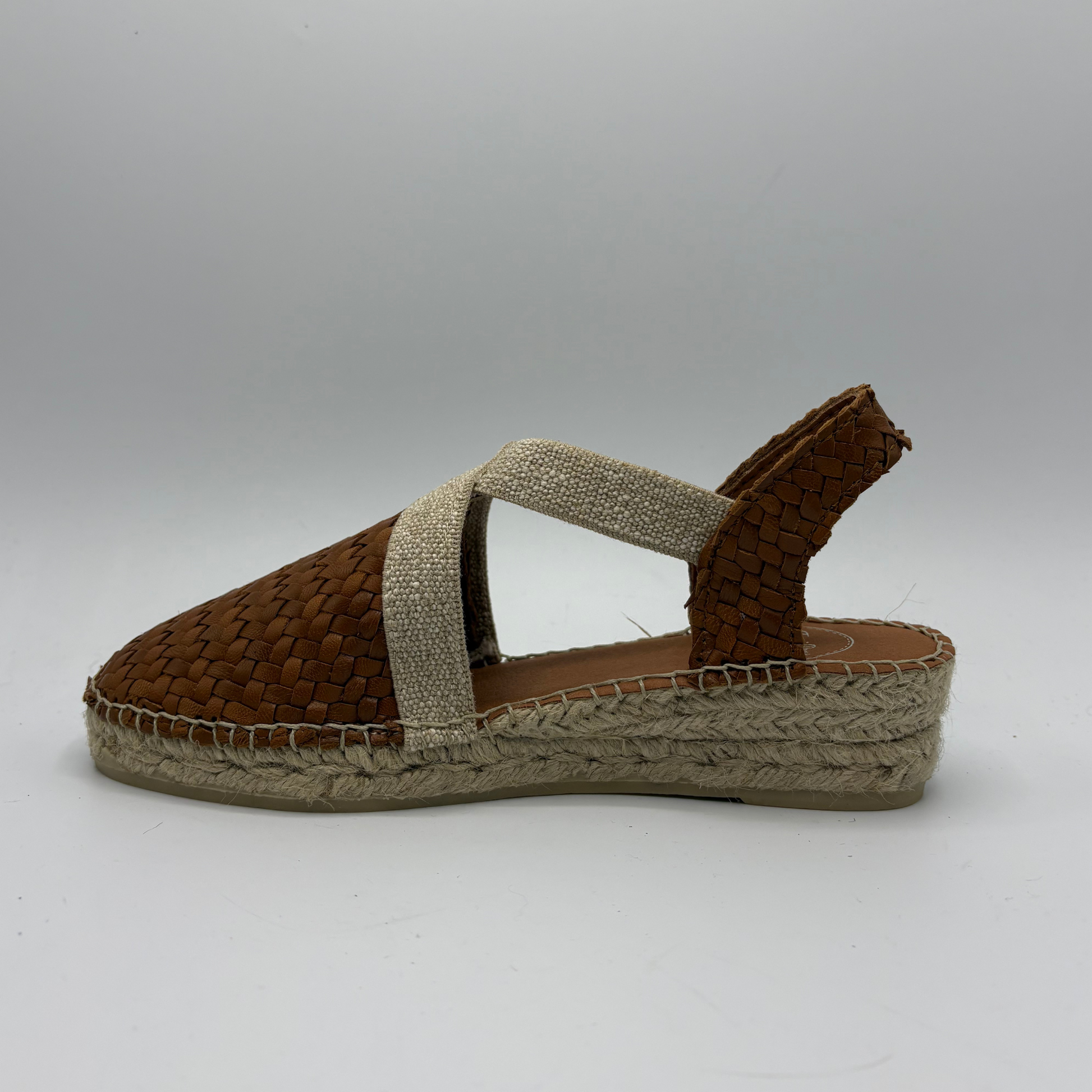 Brown woven sandal with a slingback strap on a gray background