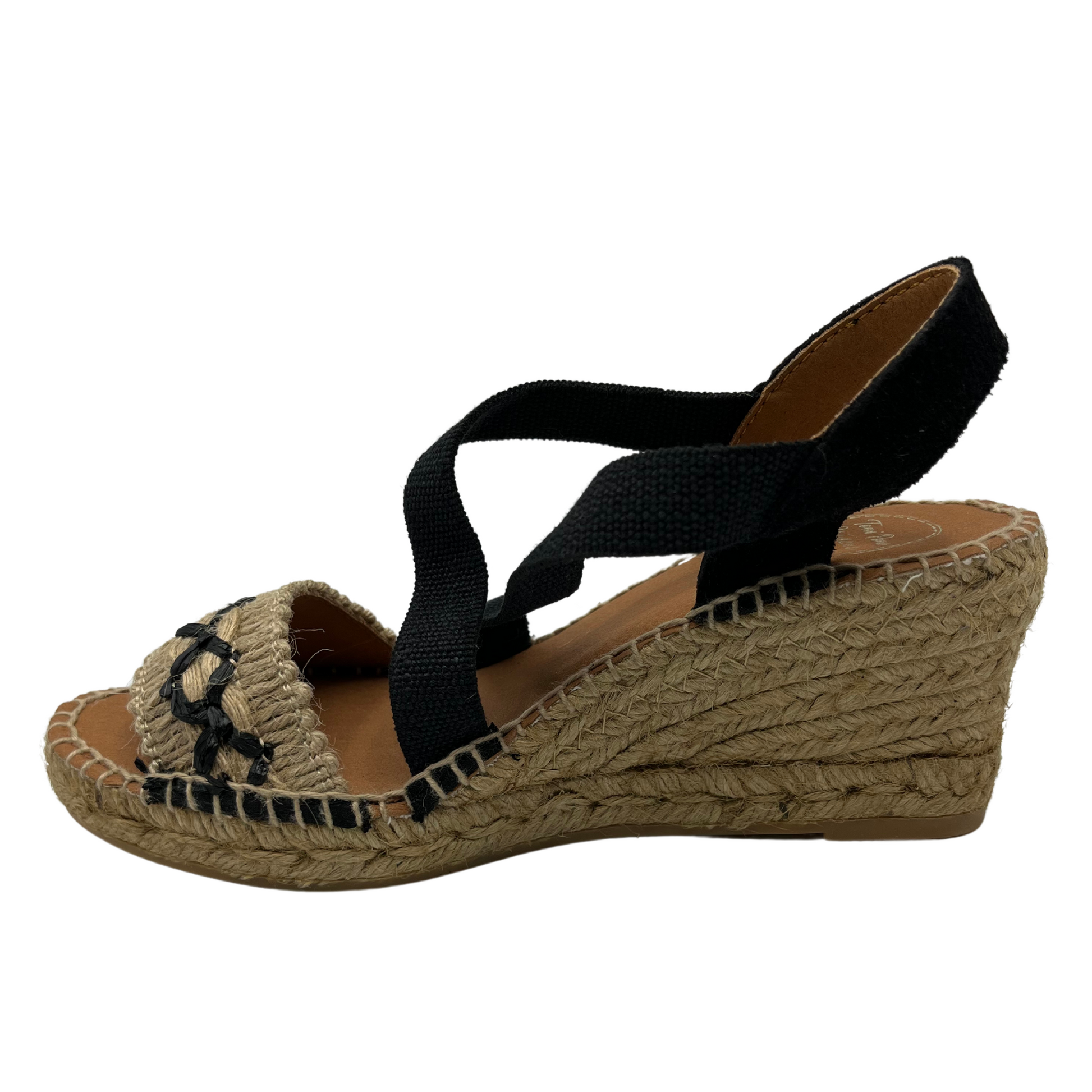 Left facing view of black and beige wedge sandal with X pattern across toe