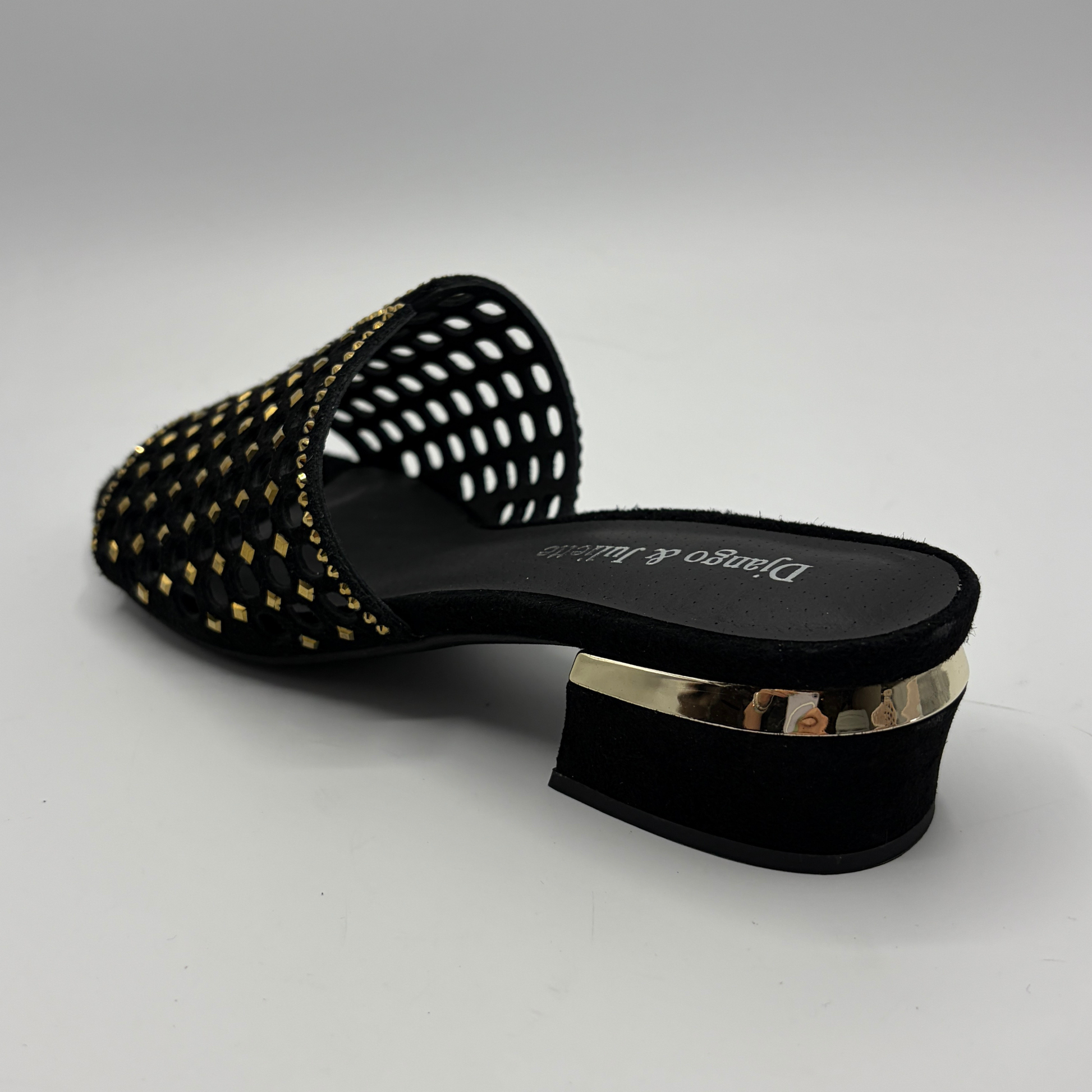 Black sandal with gold accents on a gray background