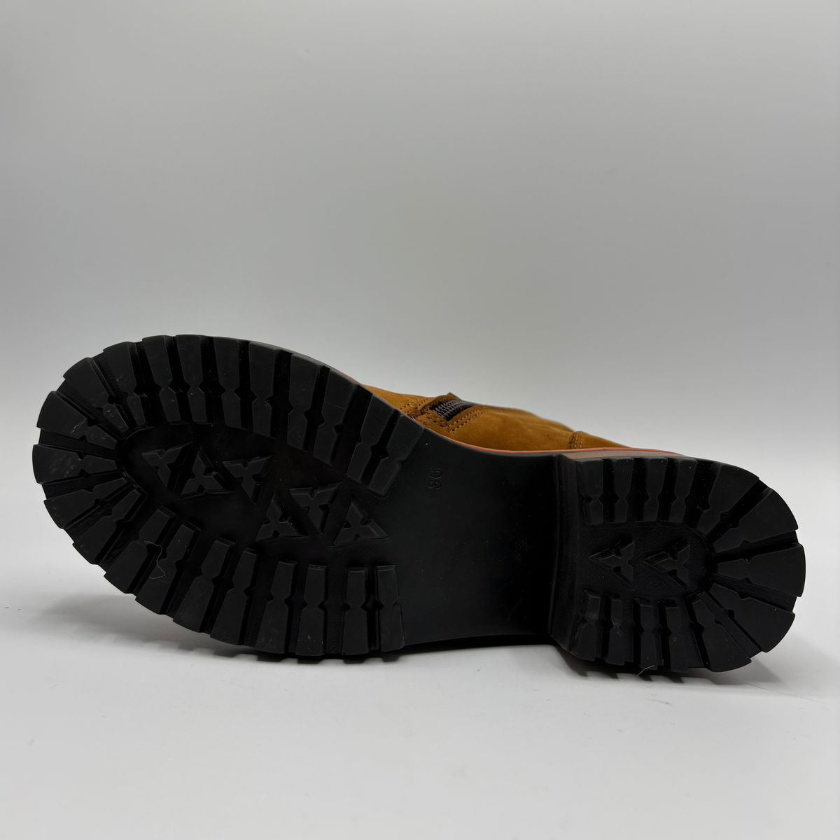 Bottom view of a tan suede boot with a stacked heel, elastic side panel and matching laces