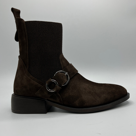 Brown suede boot with a buckle on a gray background