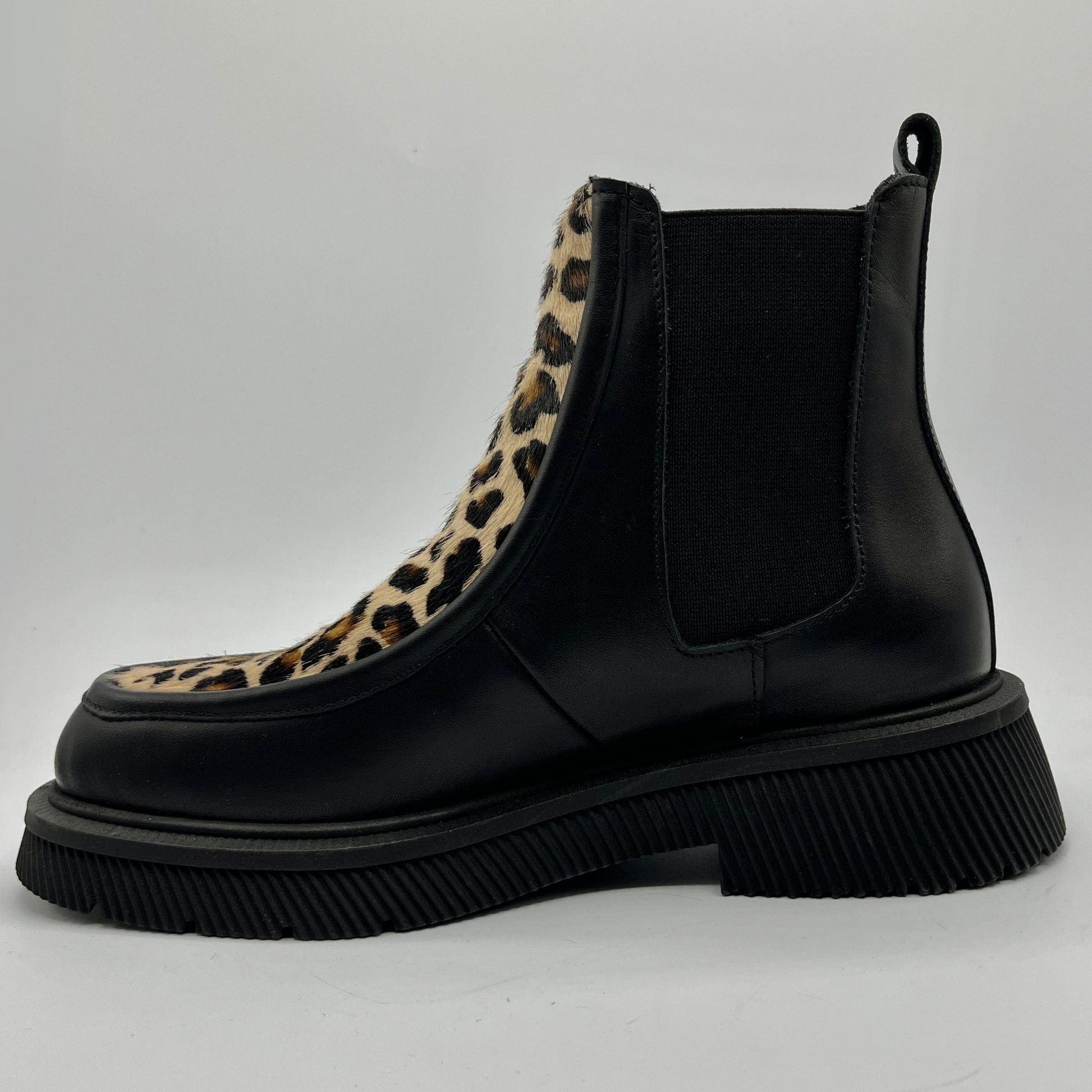 Black Chelsea boot with leopard print accent on a light gray background