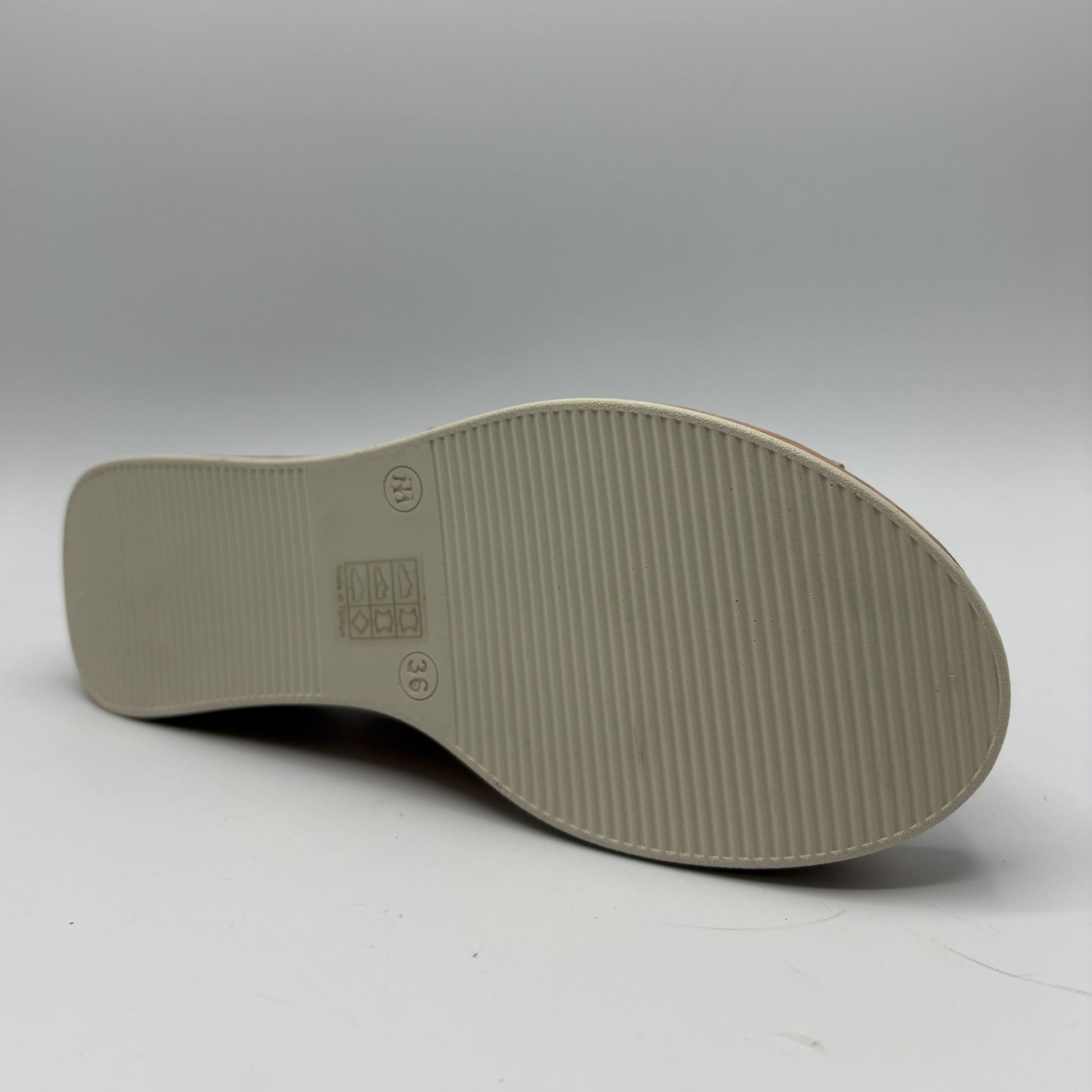 Close-up of a shoe sole with brand logo on a gray background