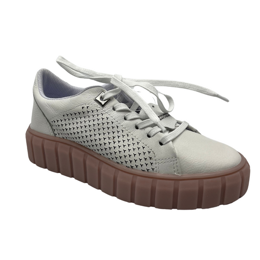 45 degree angled view of white leather sneakers with rose coloured platform rubber outsole. White laces and perforated leather details on the sides.