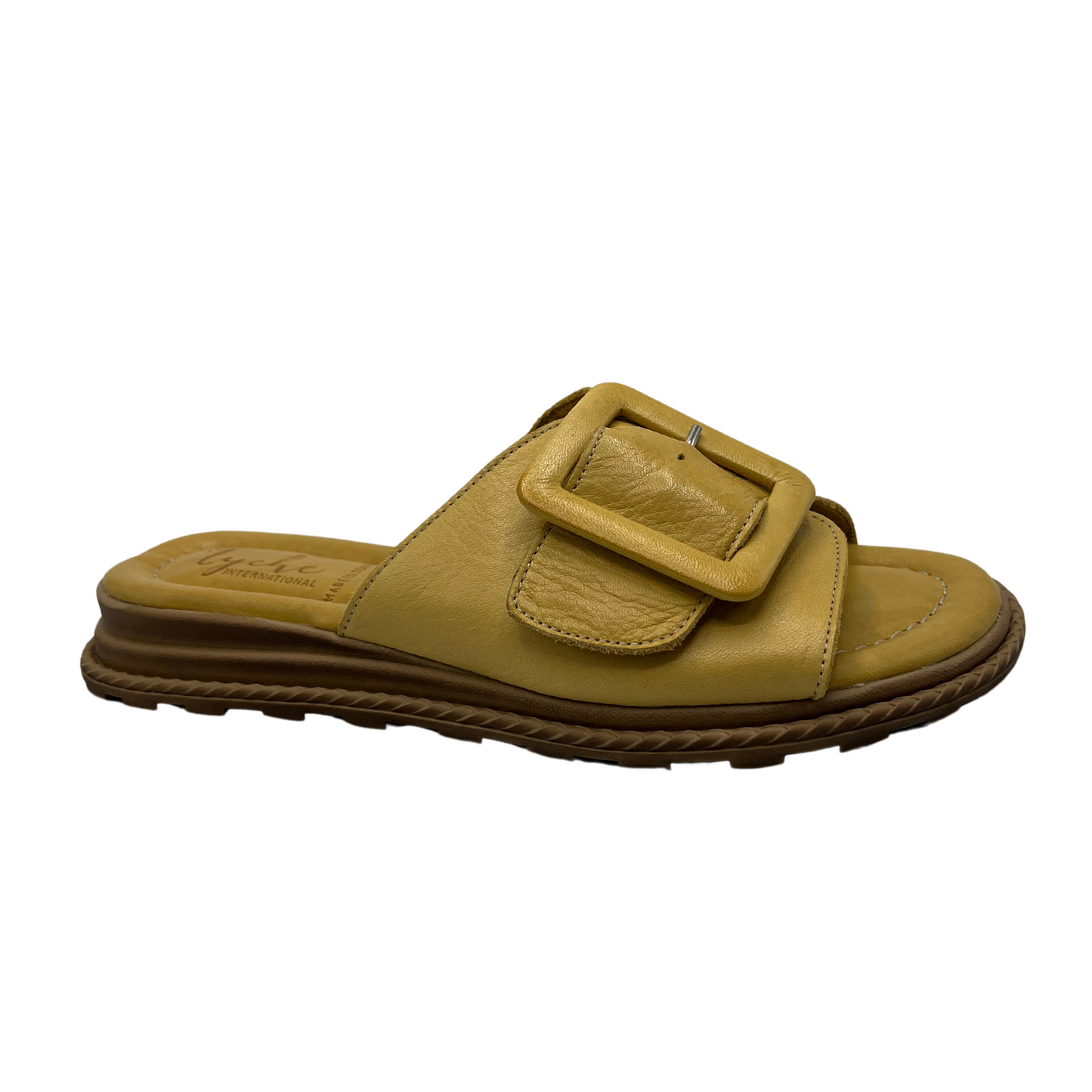 Angled view of yellow leather sandal with oversized buckle on strap. Leather lined, cushioned footbed and open toe