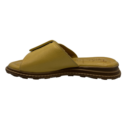Left facing view of yellow leather sandal with oversized buckle on strap. Leather lined, cushioned footbed and open toe