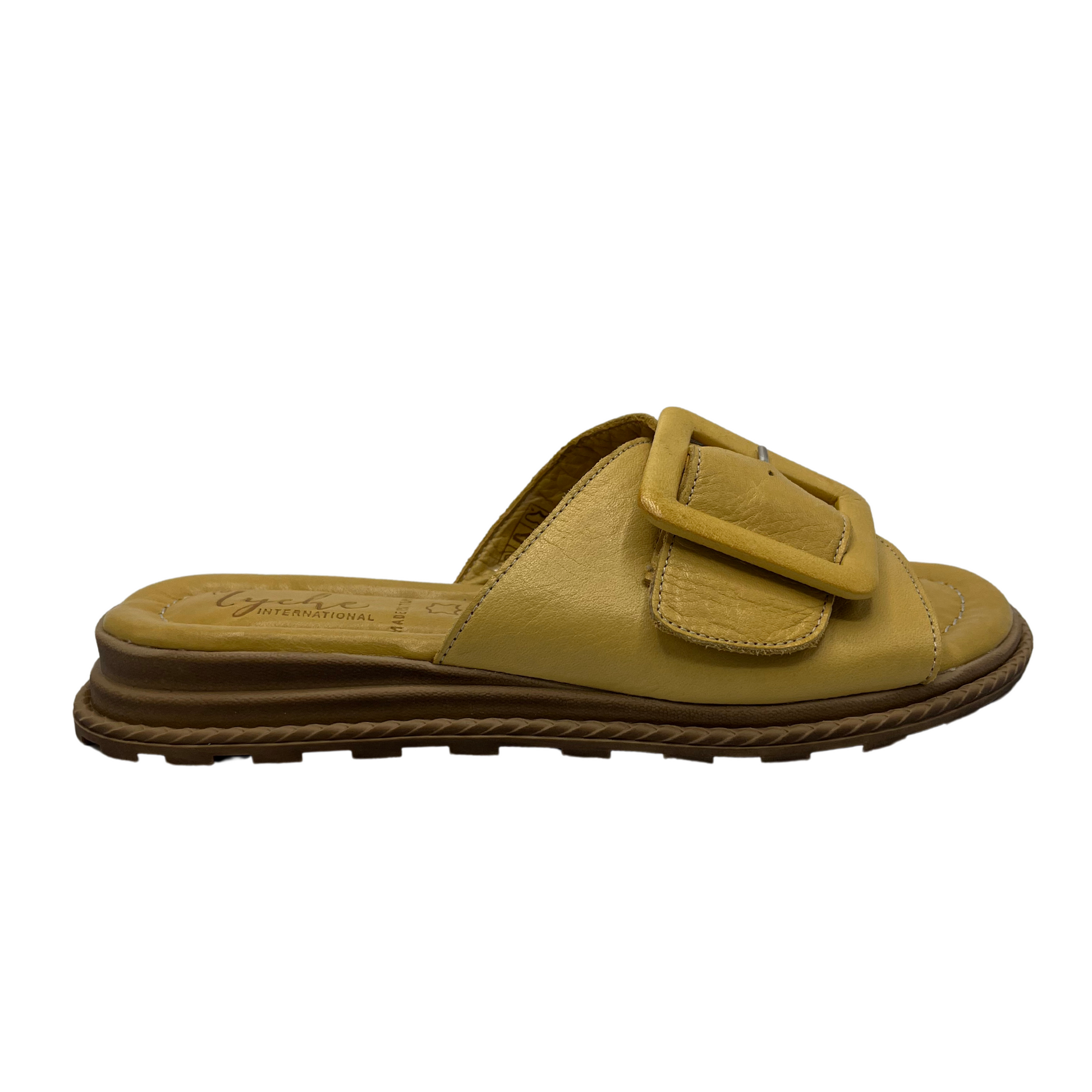 Right facing view of yellow leather sandal with oversized buckle on strap. Leather lined, cushioned footbed and open toe