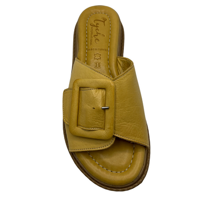 Top view of yellow leather sandal with oversized buckle on strap. Leather lined, cushioned footbed and open toe