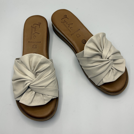 Pair of beige sandals with knotted design on a white background