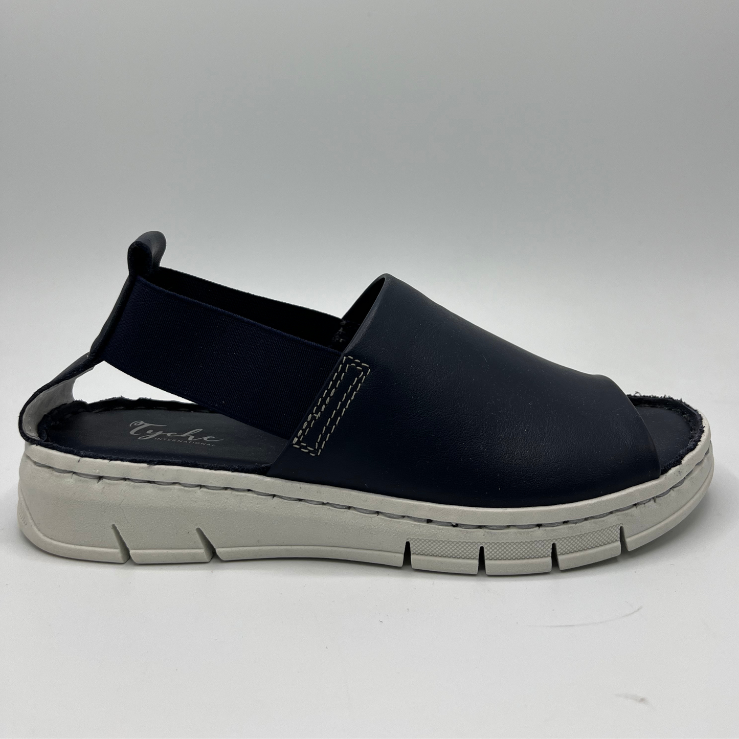 Right facing view of a slip on shoe with elasticated side bands, peep toe and a white rubber outsole.