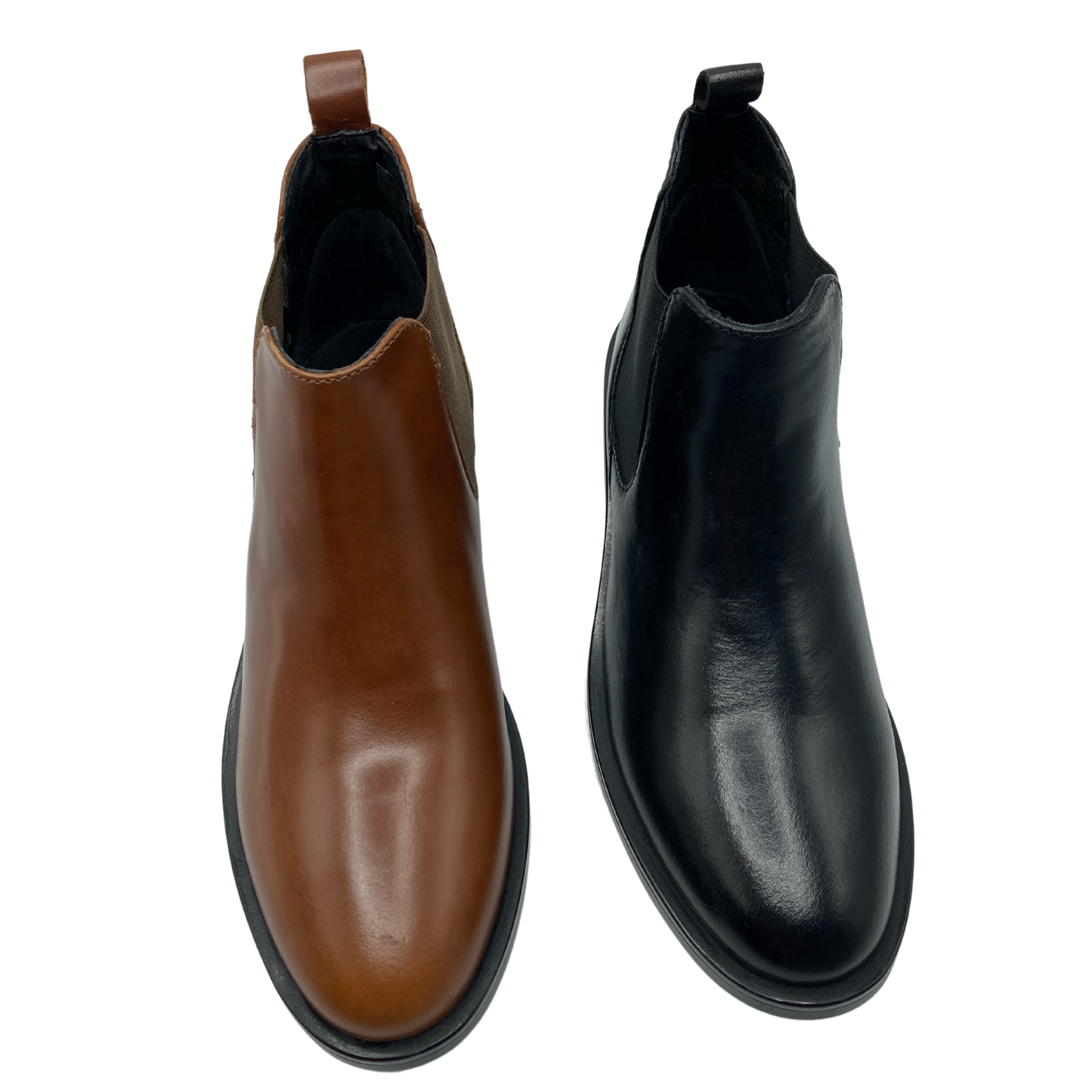 Top view of a pair of leather chelsea boots, the one on the left is tan and the one on the right is black. Both have black outsoles and elastic side gores