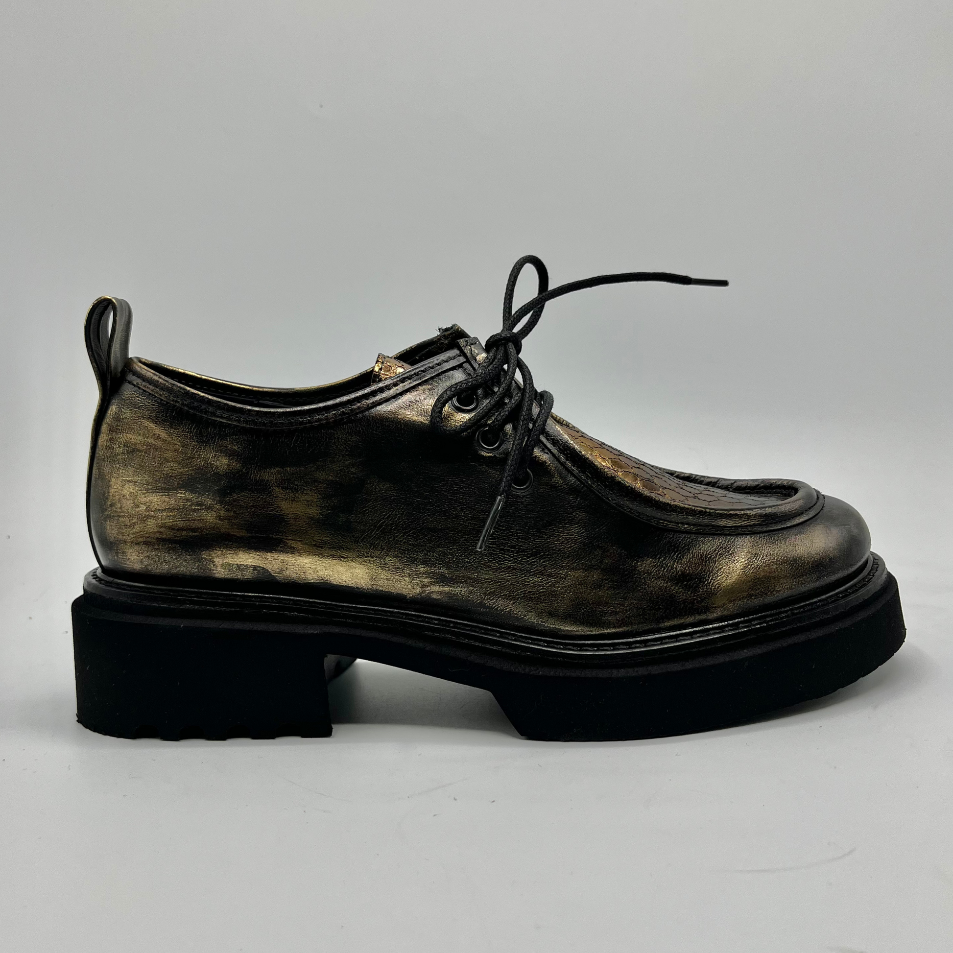 Gold colour leather shoe with a thick sole on a light gray background