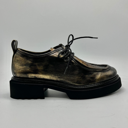 Gold colour leather shoe with a thick sole on a light gray background