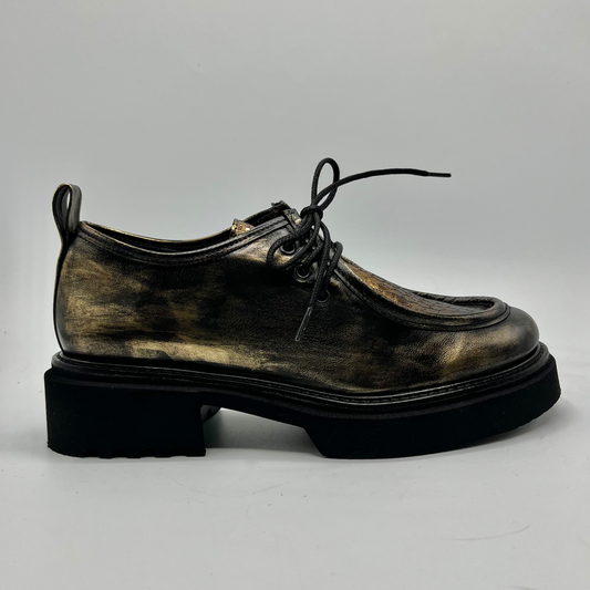 Gold colour leather shoe with a thick sole on a light gray background