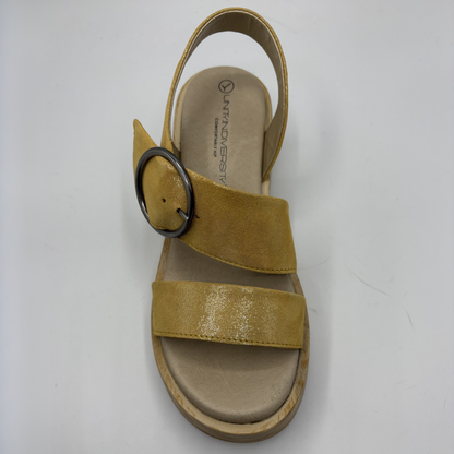 Yellow sandal with a black circular buckle on a white background