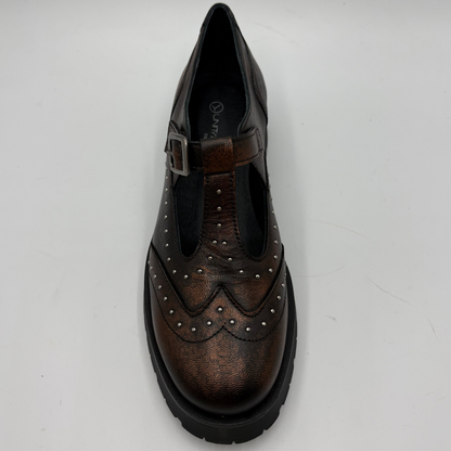 A single brown distressed leather T-strap Mary Jane shoe with silver stud detailing and a black chunky lug sole, shown from the top view on a light gray background.