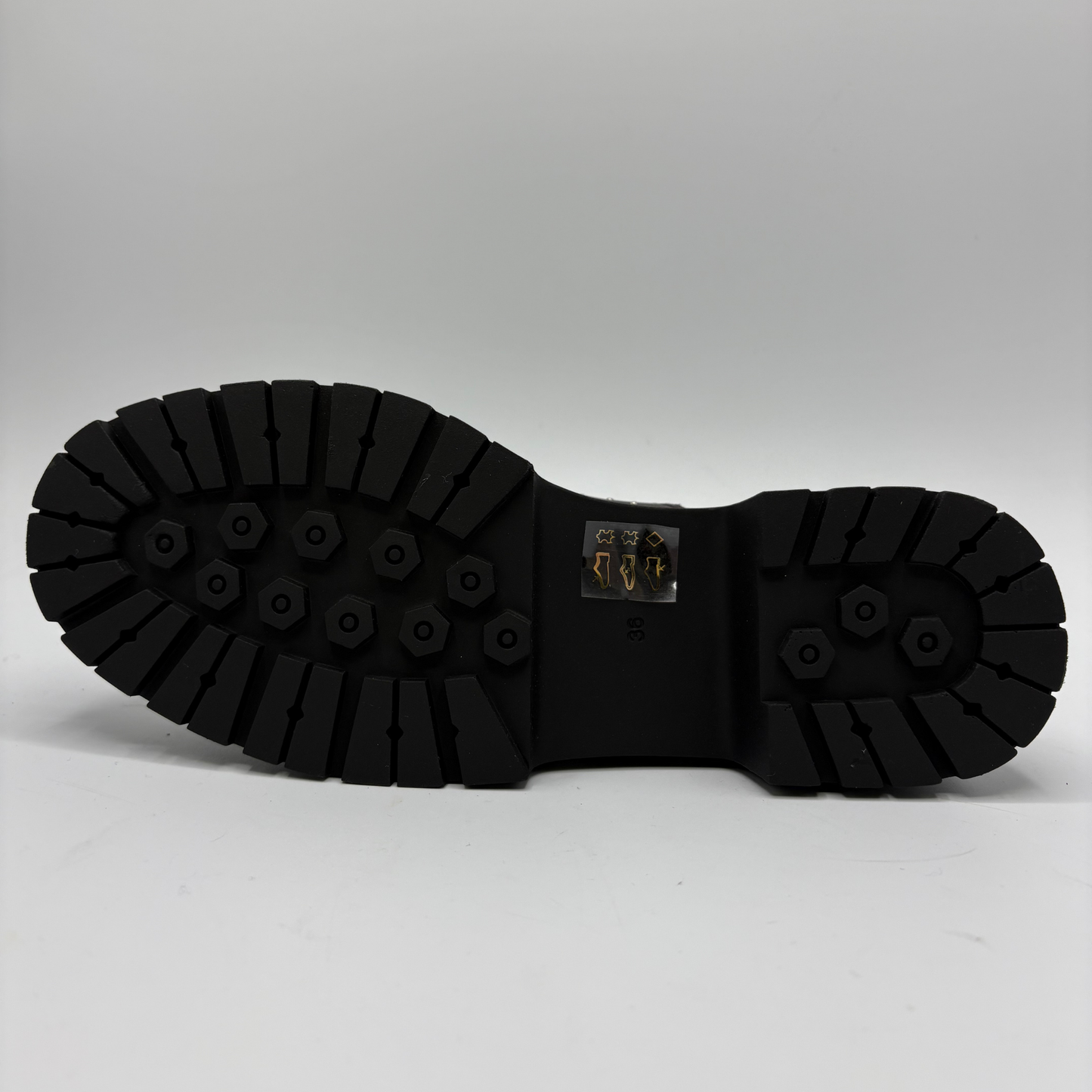 A single brown distressed leather T-strap Mary Jane shoe with silver stud detailing and a black chunky lug sole, shown from the bottom on a light gray background.