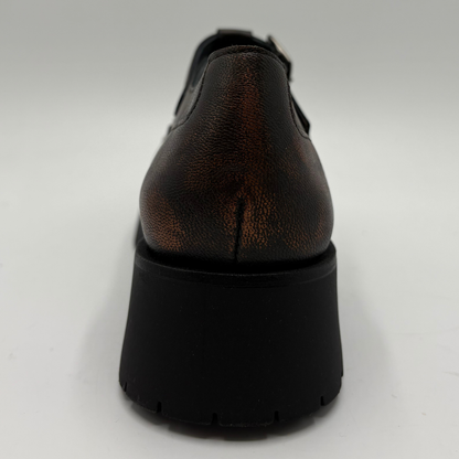A single brown distressed leather T-strap Mary Jane shoe with silver stud detailing and a black chunky lug sole, shown from the back on a light gray background.