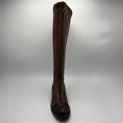 A single knee-high brown leather boot with a dark brown crocodile textured toe cap and a black sole, shown from the front  against a light gray background.