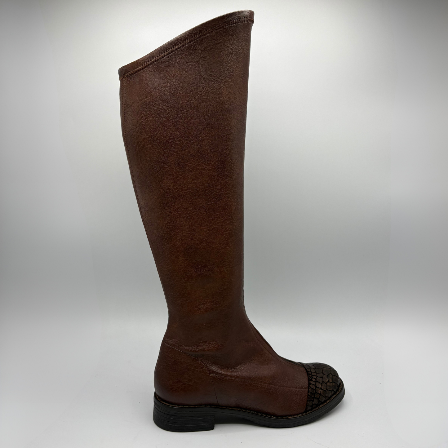 A single knee-high brown leather boot shown from the side against a light gray studio background. The boot features a smooth brown leather shaft and a brown crocodile-embossed toe cap.