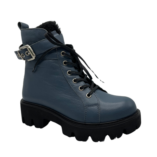 45 degree angled view of sky blue leather boot with silver buckle on the ankle strap. black lug sole and side zipper closure.