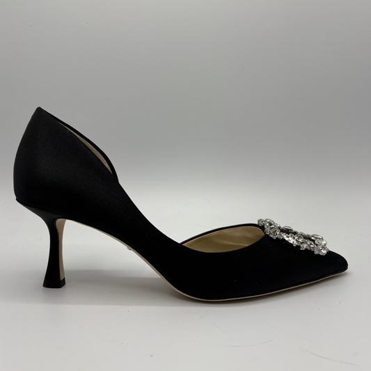 Black high-heeled shoe with a decorative embellishment on a gray background
