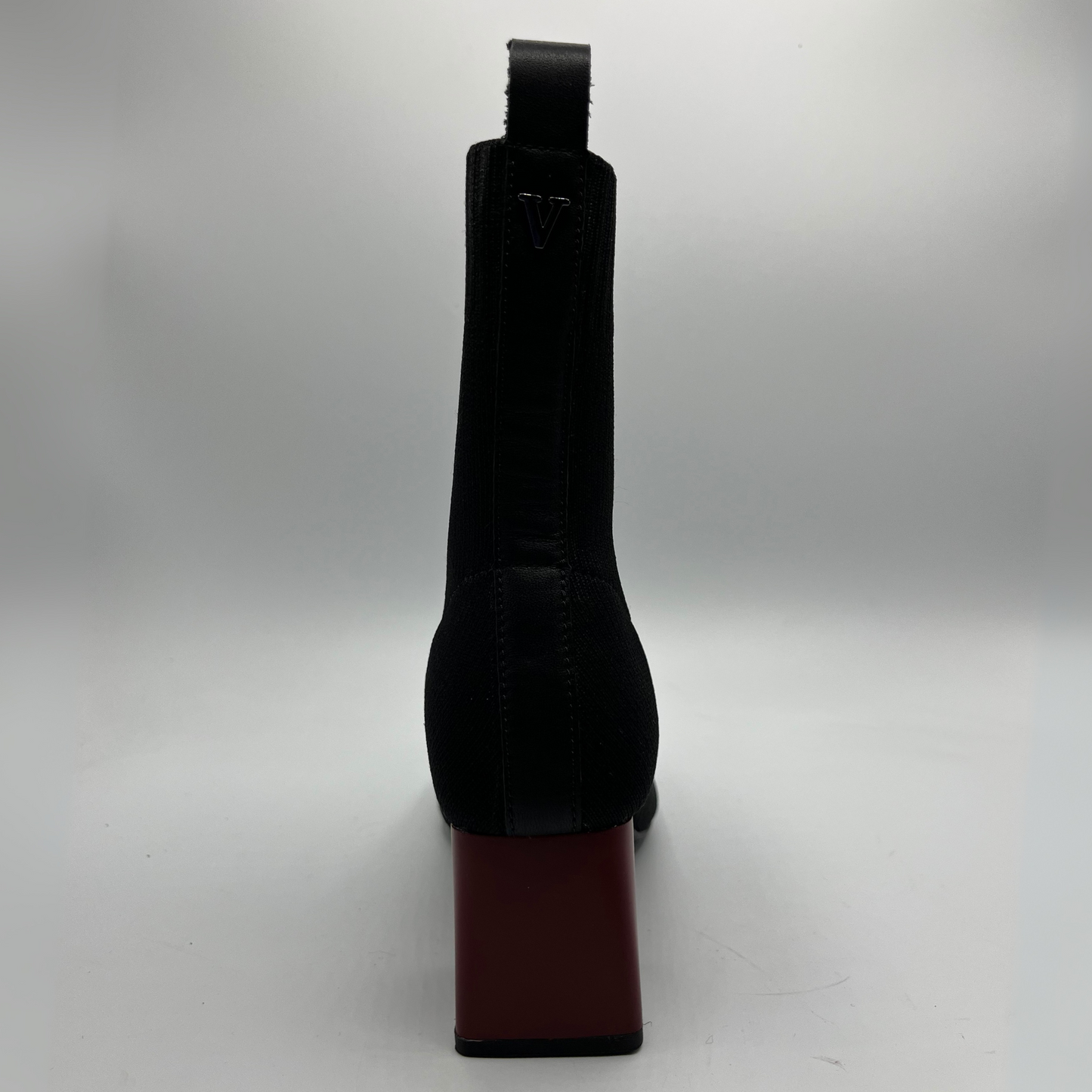 Black boot with a red sole on a white background