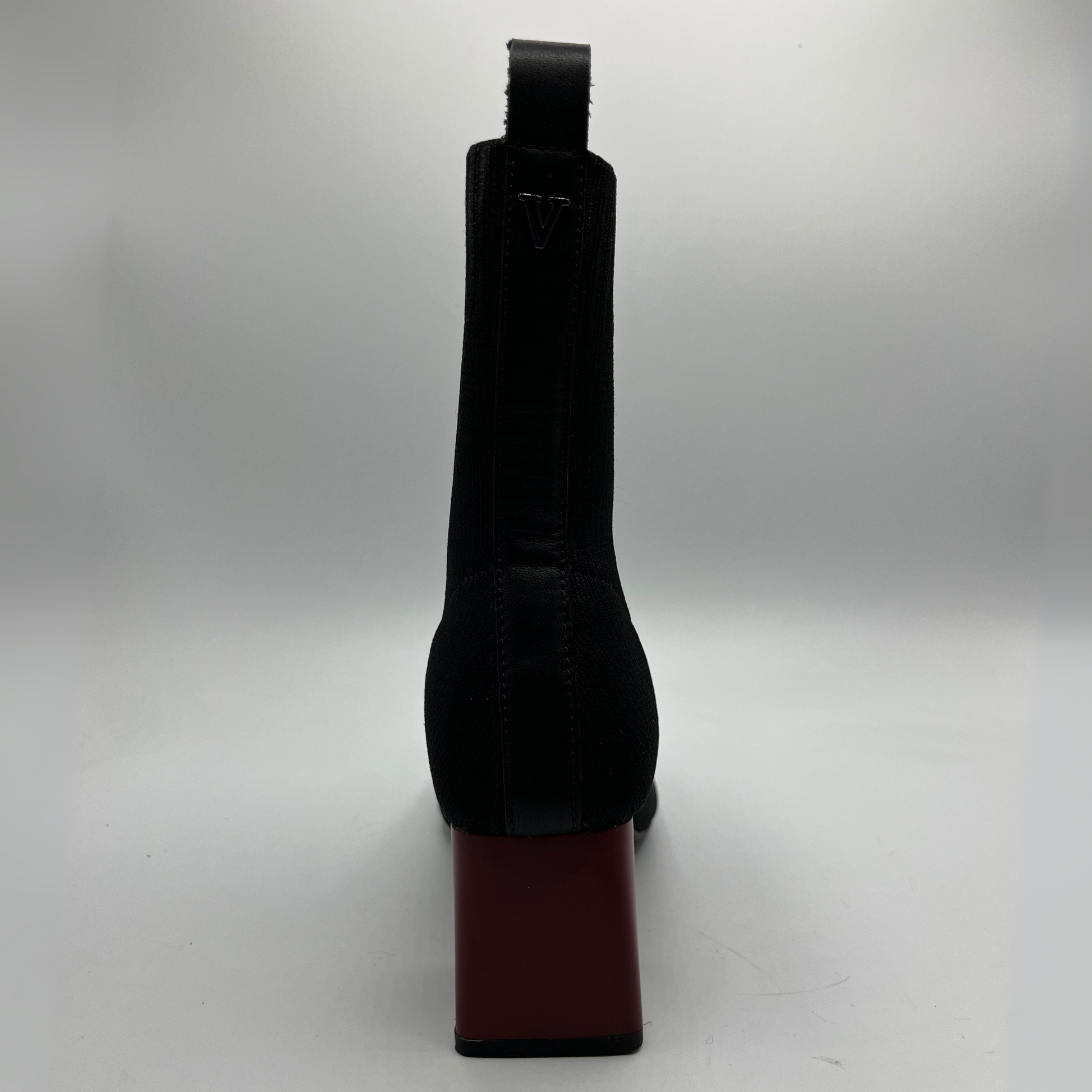 Black boot with a red sole on a white background