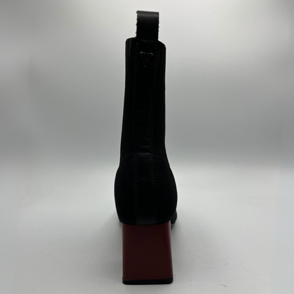 Black boot with a red sole on a white background