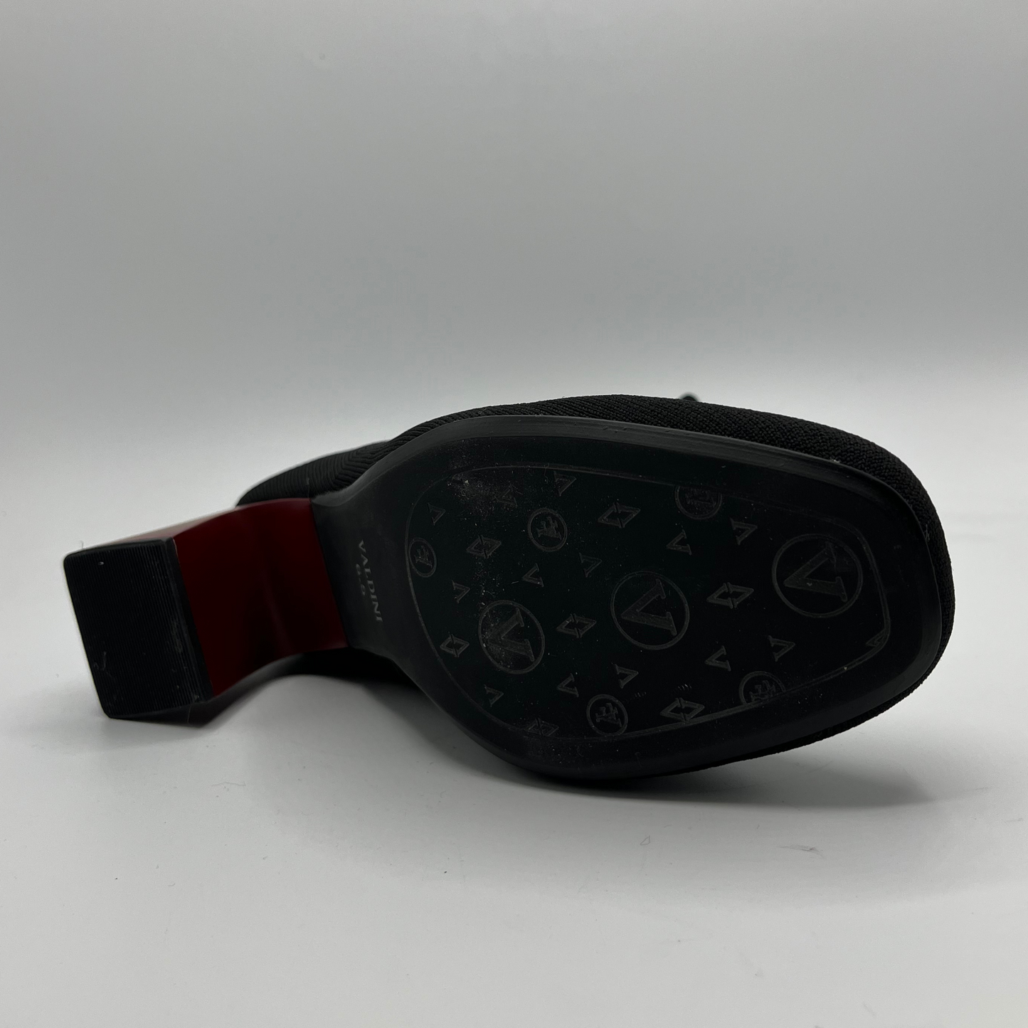 Black boot with a red sole on a gray background