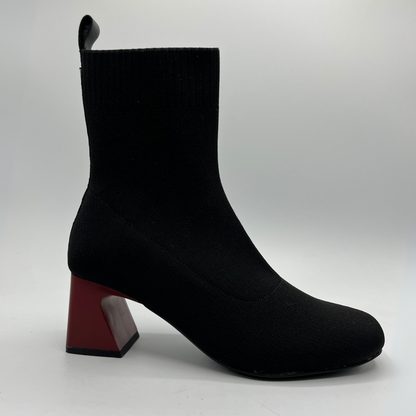 Black ankle boot with a red block heel on a white background