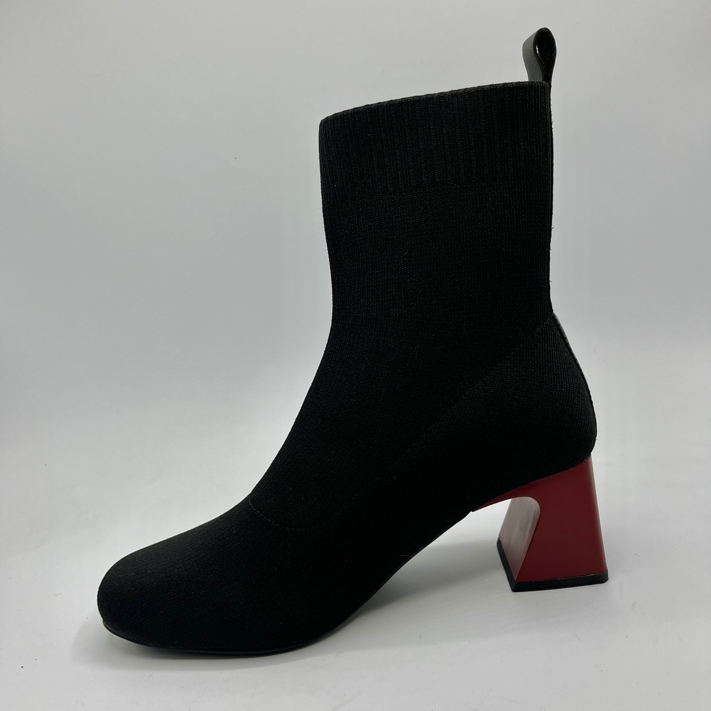Black sock boot with a red block heel on a white background