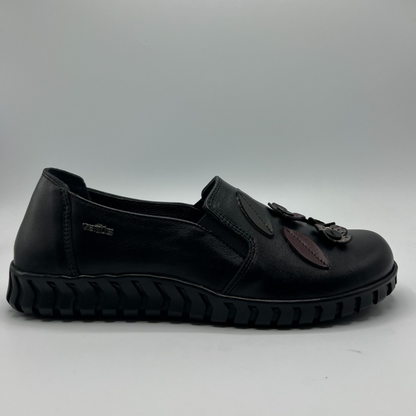 Black shoe with leather accents on a gray background