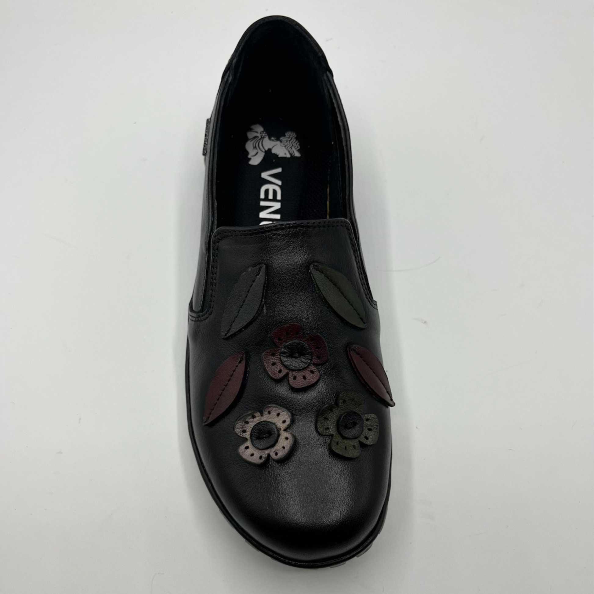 Black slip-on shoe with floral designs on a white background