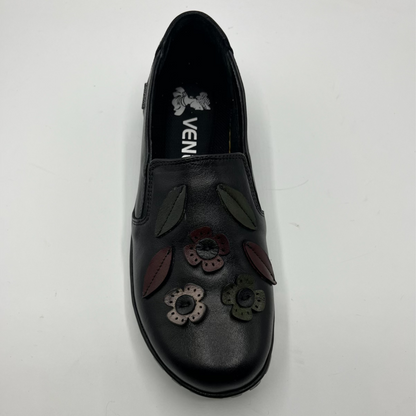 Black slip-on shoe with floral designs on a white background