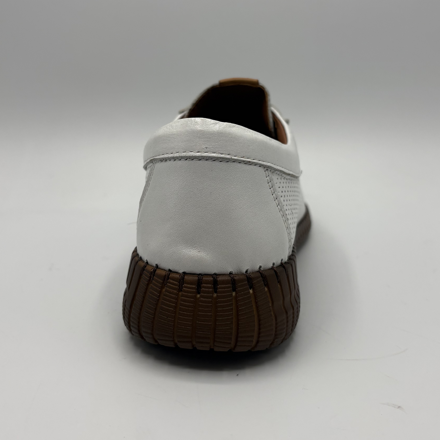 White shoe with brown sole on a light gray background