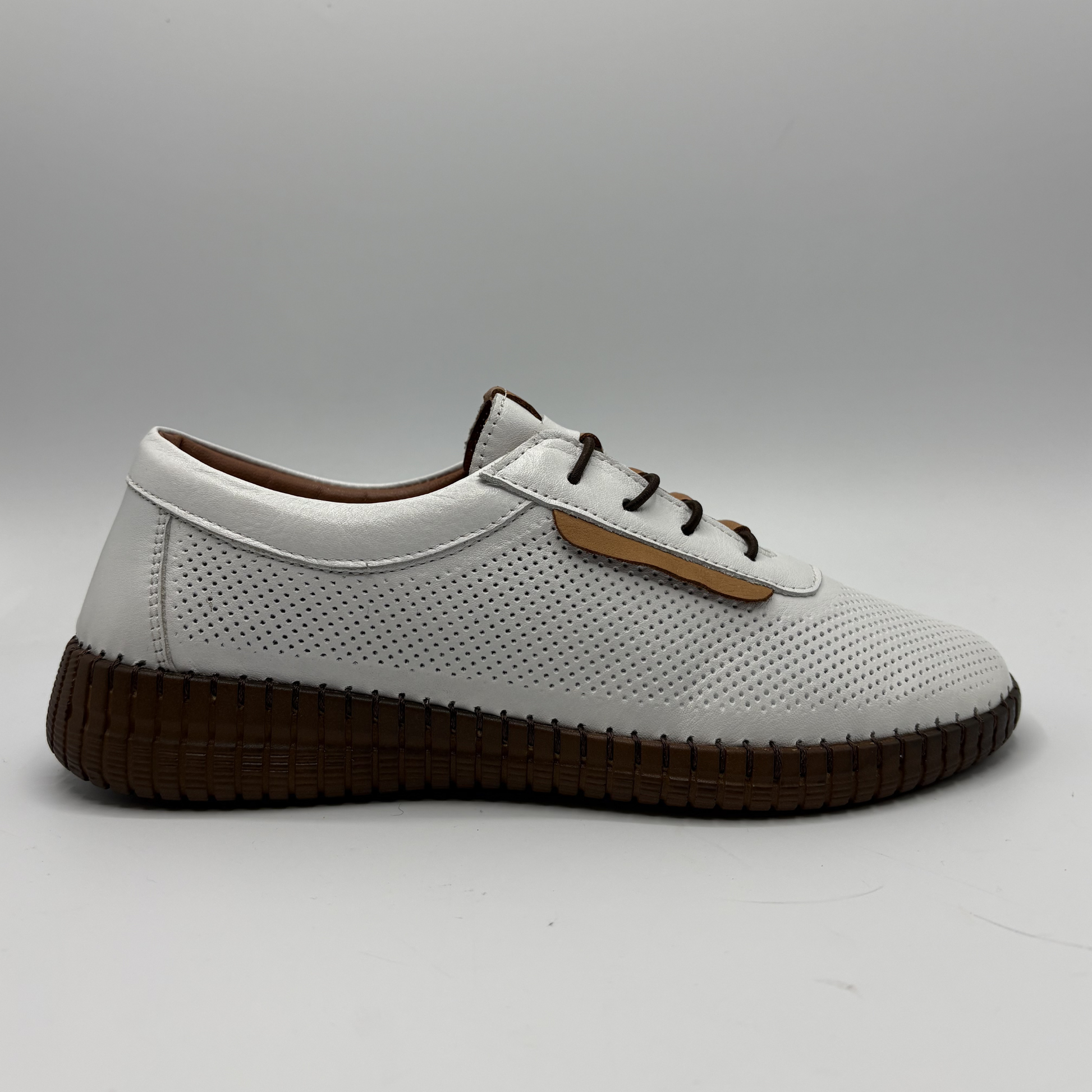 White sneaker with brown sole on a gray background