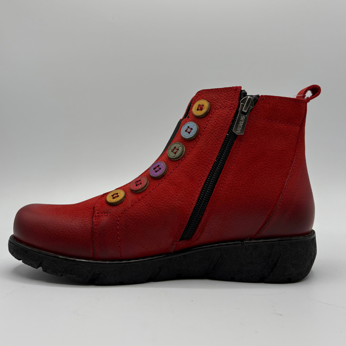 Left facing view of a red short boot with colourful buttons, a black outsole and a pull on heel tab
