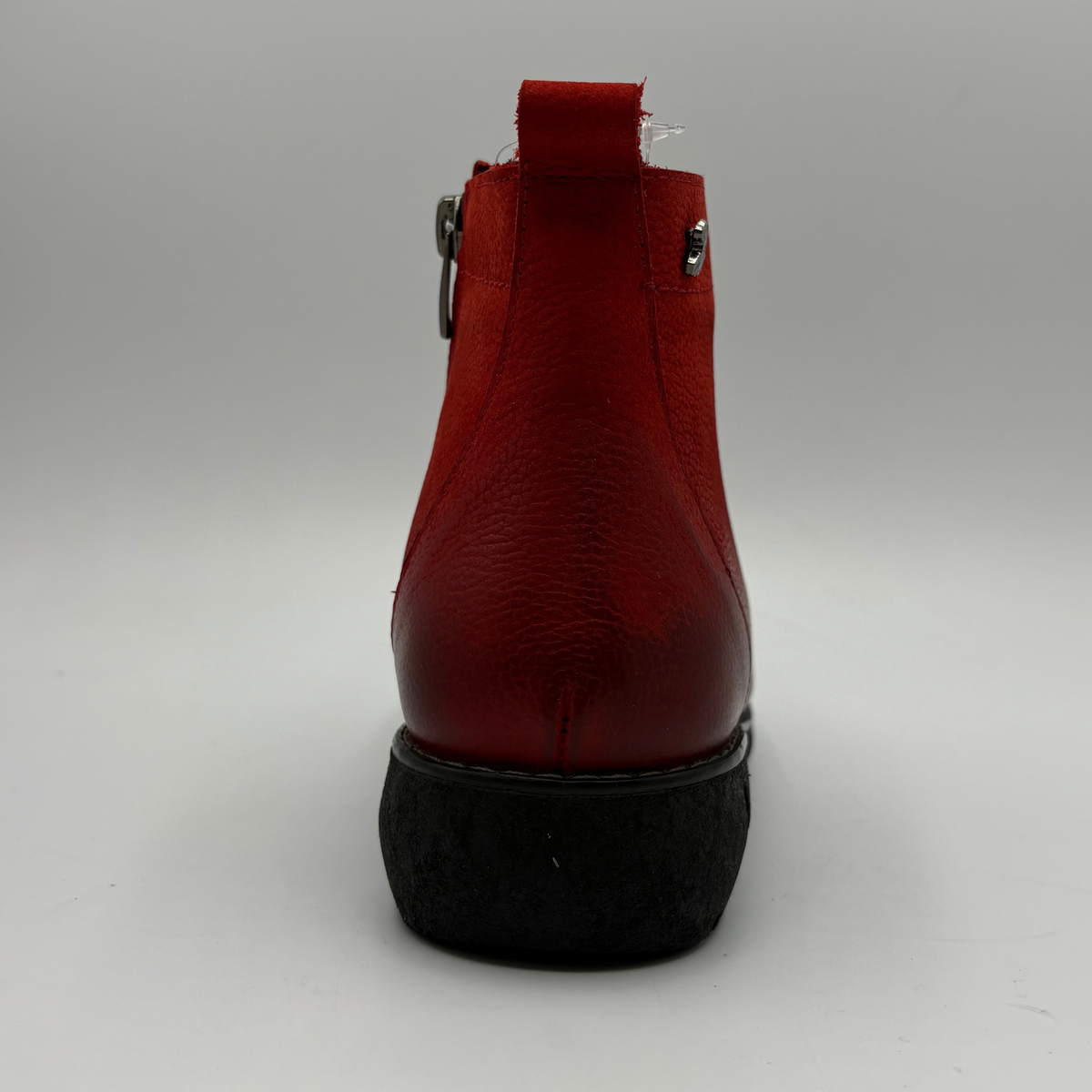 Back view of a red short boot with colourful buttons, a black outsole and a pull on heel tab