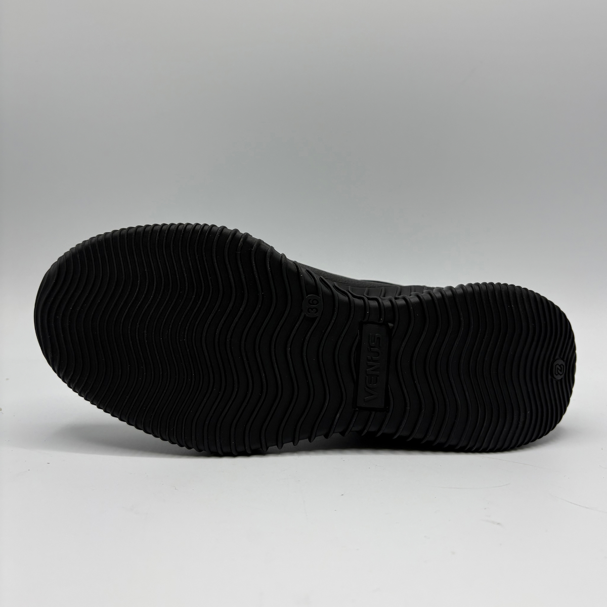 Bottom view of a black leather sneaker with a supportive outsole